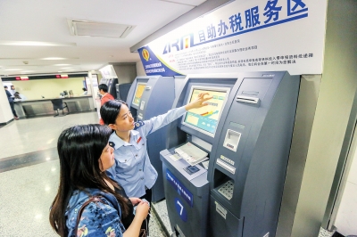 图片说明：在工作人员的帮助下，企业办税人员在自助机上打印发票。